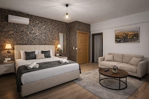 Habitación de hotel con cama, sofá, mesa de centro, un cuadro y una puerta.