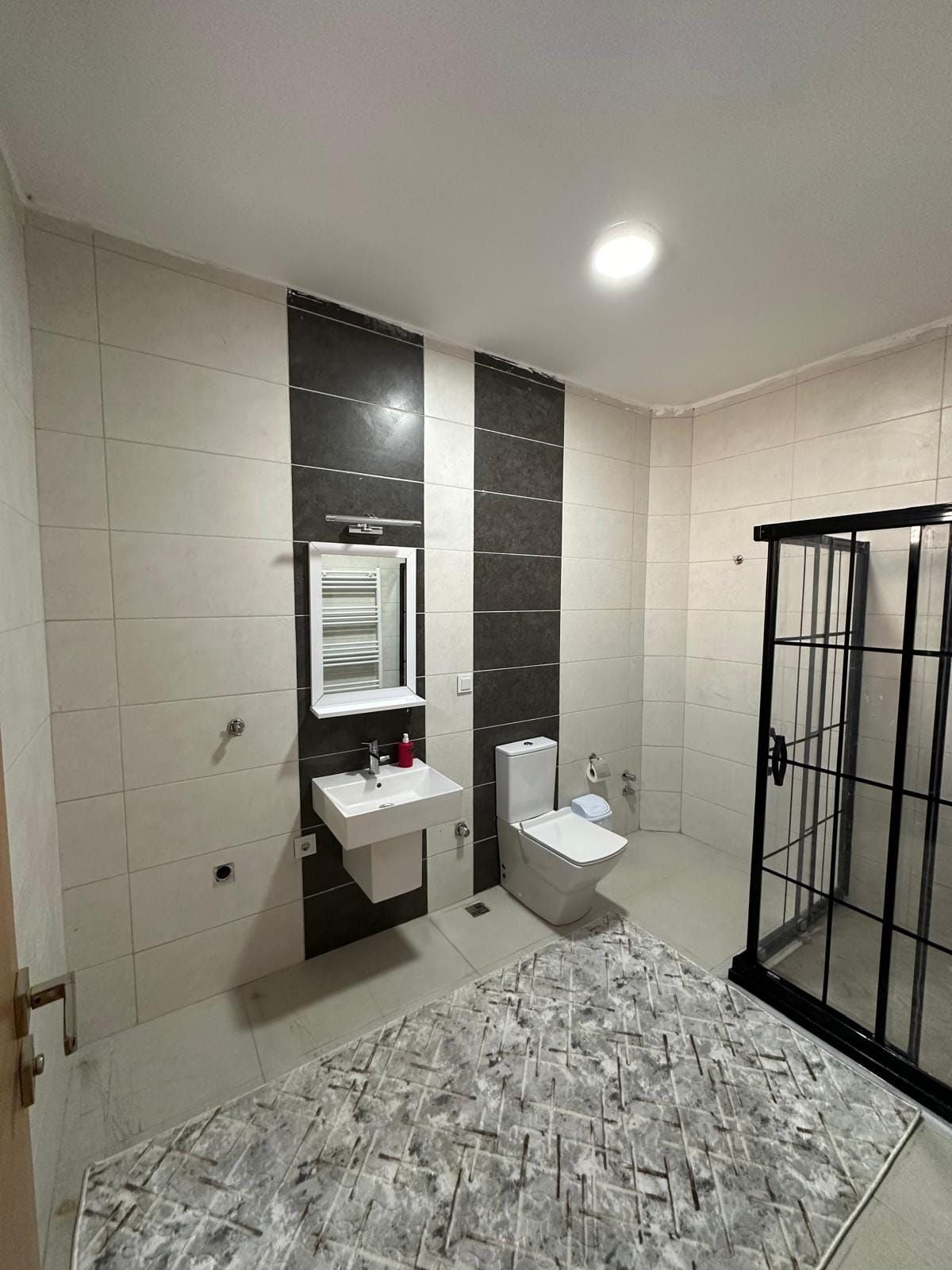 Un baño con lavamanos blanco, inodoro y cabina de ducha.