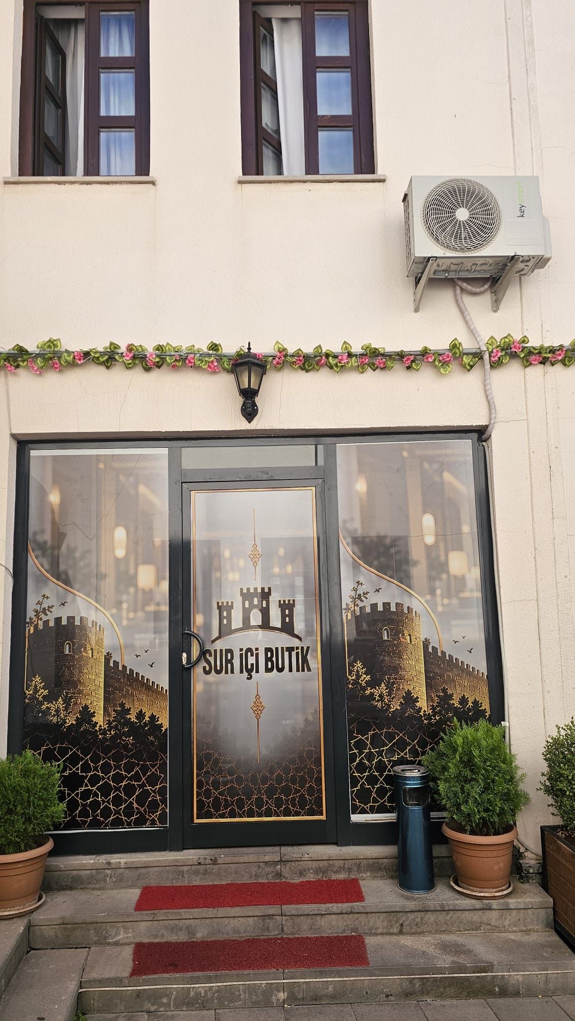 A hotel entrance with a glass door featuring a castle illustration and the text 'SUR İÇİ BUTIK'.