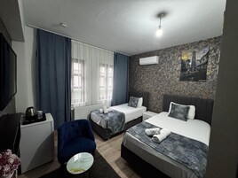 Habitación de hotel con dos camas, un escritorio, una silla y un radiador.