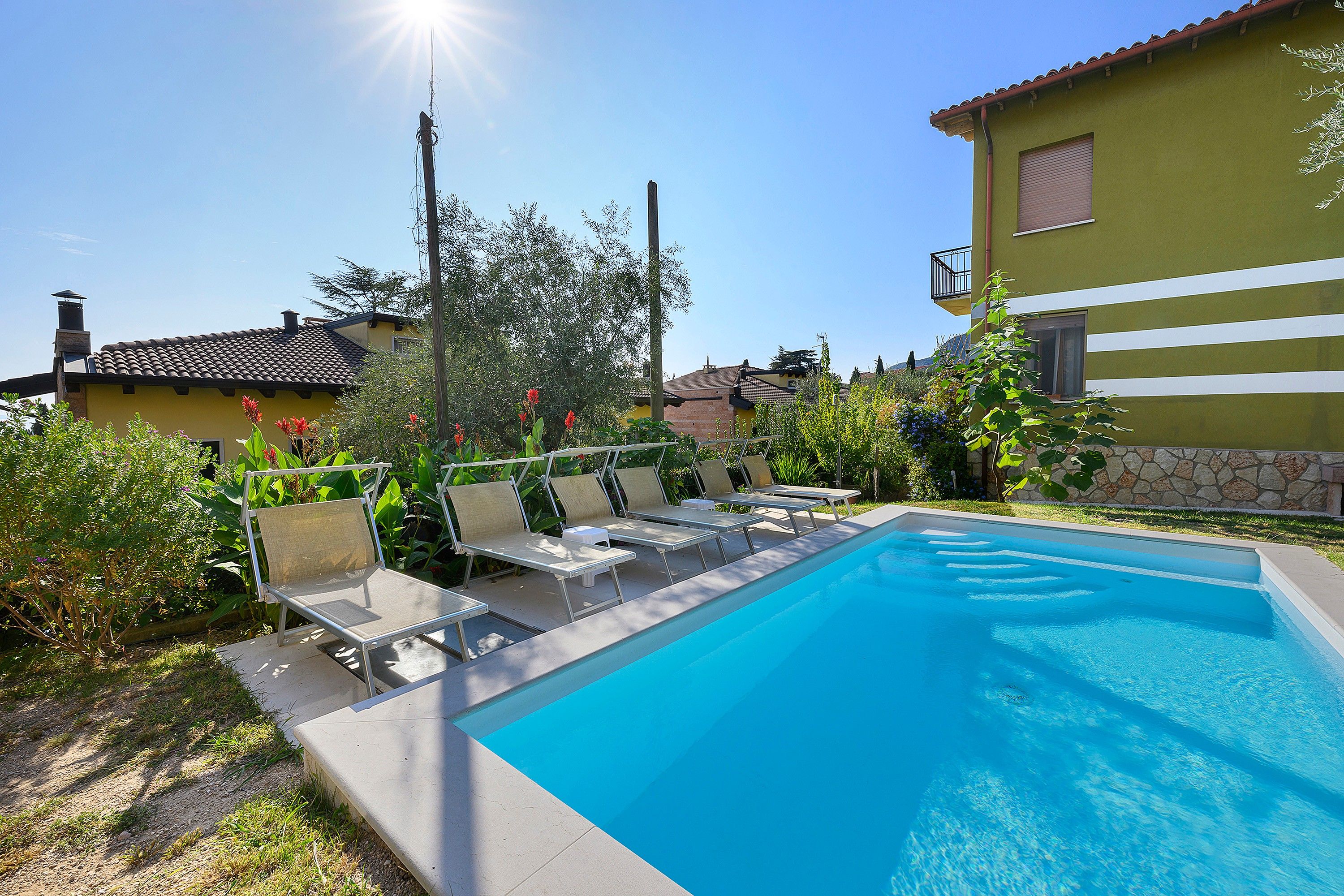Une piscine avec des chaises longues et un ciel bleu azur.