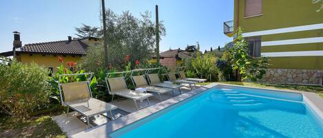 A swimming pool with lounge chairs and a clear blue sky.