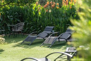 Outdoor seating with chairs and a table, surrounded by lush greenery and flowering plants. - Room 'Double  7' with Wi-Fi and air conditioning (Cercal)