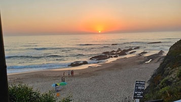 A beach view with a sunset, rocky shoreline, and a sign indicating no service.