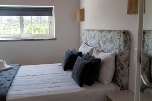A bedroom with a bed, pillows, a window, and a bedside table. - Room 'Double  with Garden View 4' with Wi-Fi, air conditioning and parking (Cercal)