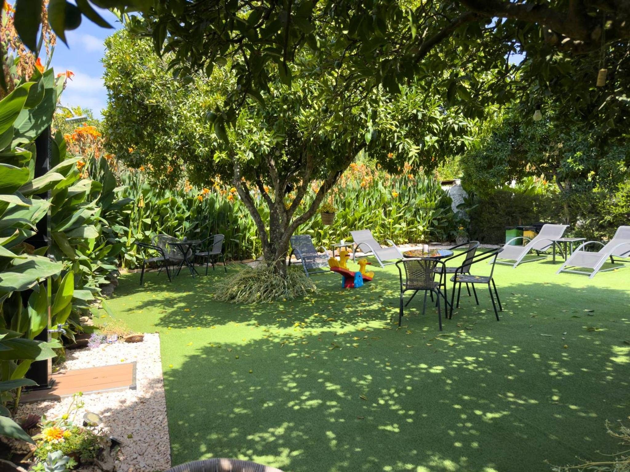An outdoor seating area with tables and chairs, surrounded by lush greenery and trees.