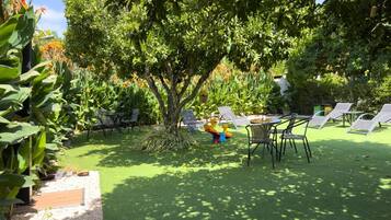 An outdoor seating area with tables and chairs, surrounded by lush greenery and trees.