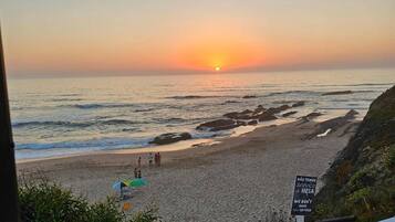 A beach view with a sunset, rocky shoreline, and a sign indicating no service.
