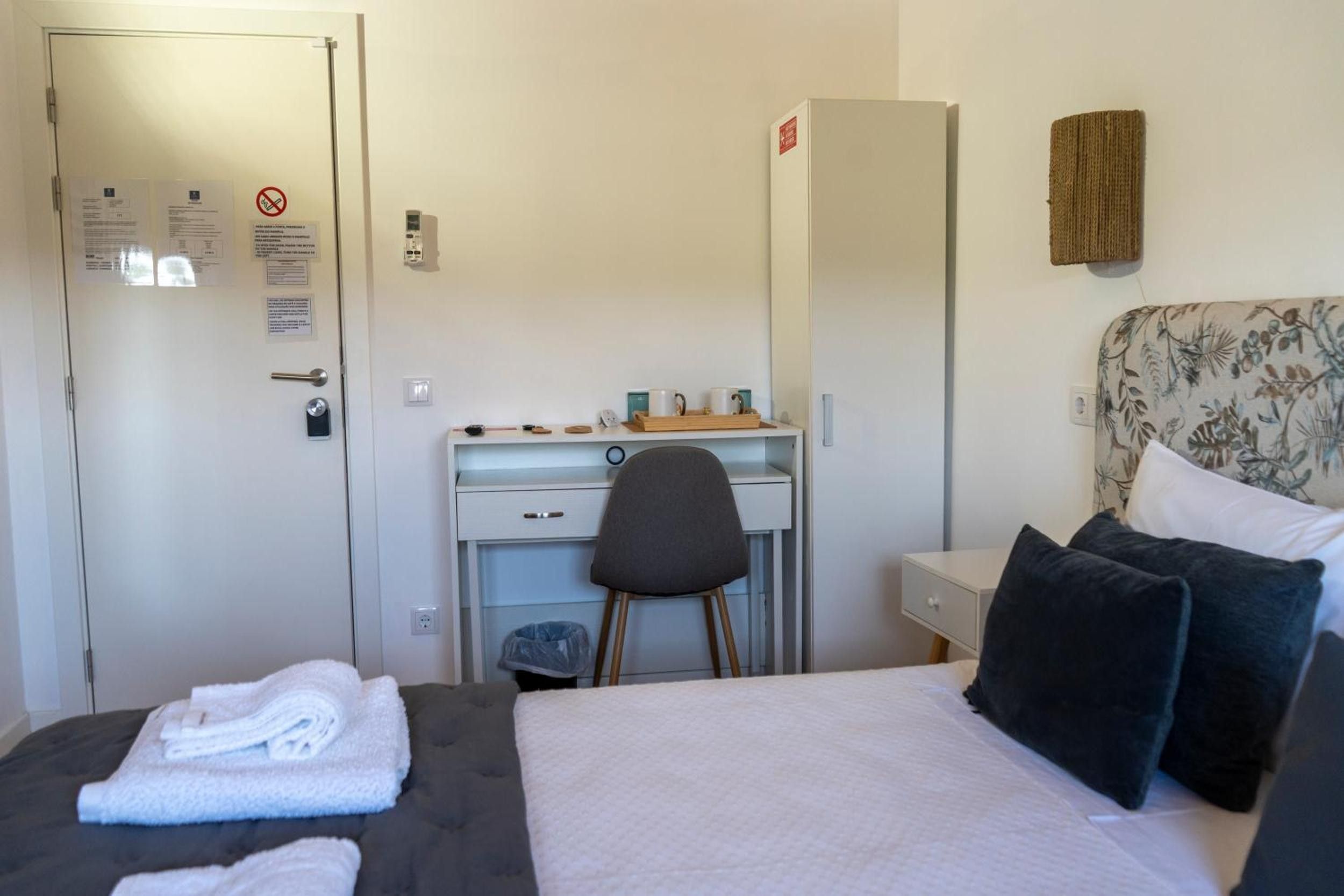 A hotel room with a bed, a desk, a chair, a wardrobe, and a bathroom door.