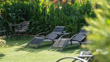 Outdoor seating with chairs and a table, surrounded by lush greenery and flowering plants.