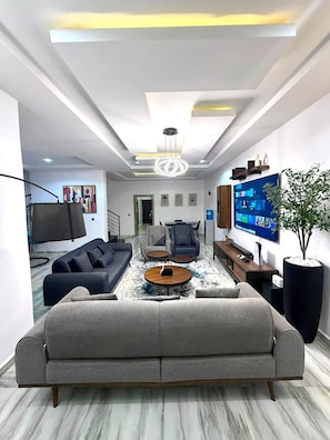 En moderne stue med en stor sofa, et sofabord og et fladskærms-tv på væggen.