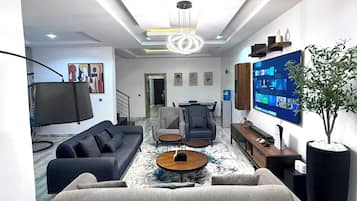 Una sala de estar moderna con un sofá, una mesa de centro, televisor y una planta grande.
