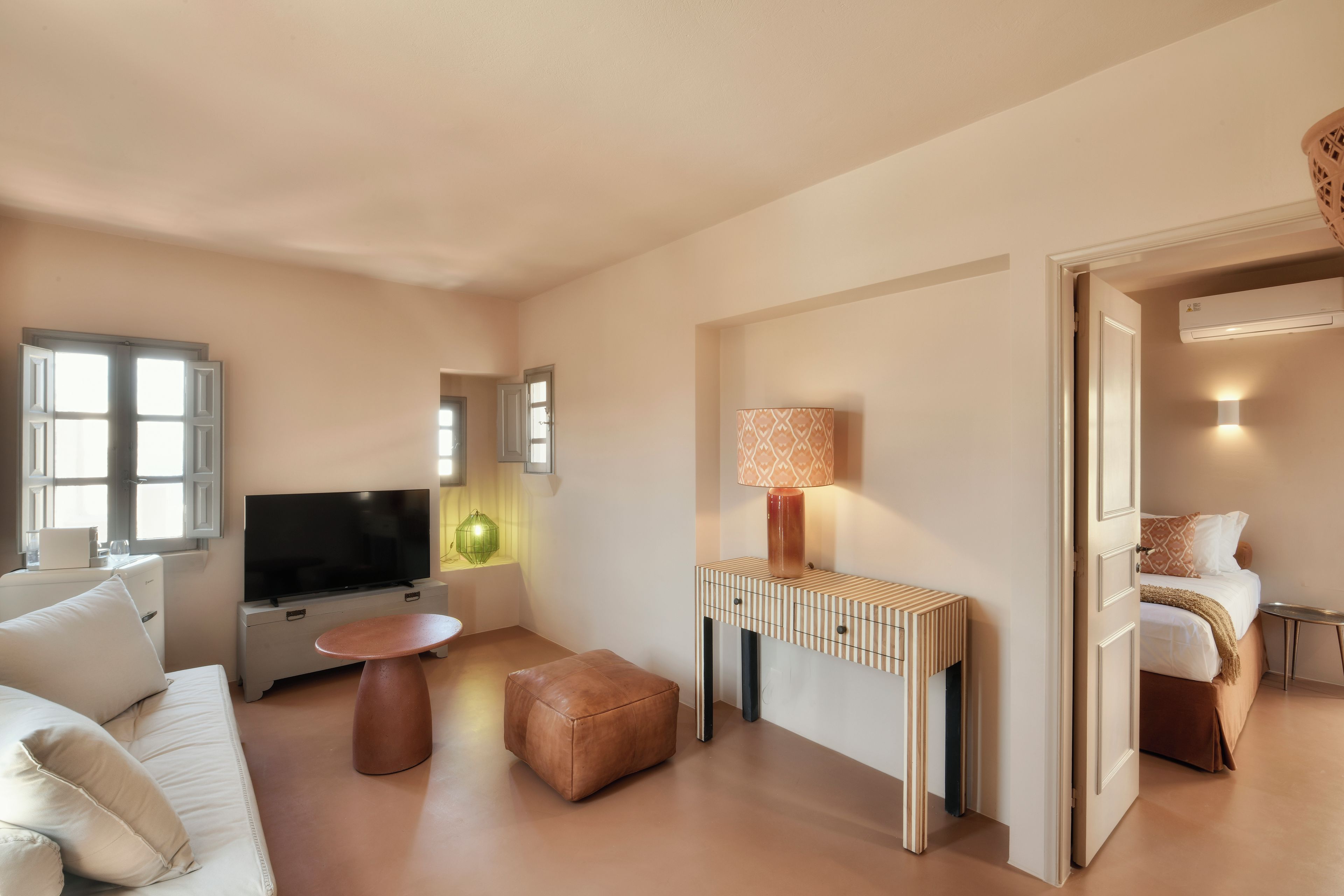 Un salon moderne avec un téléviseur à écran plat, une table basse, un canapé et un petit pouf.