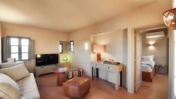 Een moderne woonkamer met een flatscreen-tv, een bank, een salontafel en een bijzettafeltje. Op een bijzettafeltje staat een lamp en in de aangrenzende kamer staat een bed.