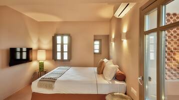 A bedroom with a bed, a TV, a lamp, and a window.