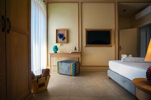Una habitación de hotel con una cama, un escritorio con silla, un televisor y una pequeña mesa con objetos decorativos.