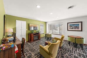 A well-lit room with a television, a fireplace, a dining area with chairs, and a carpeted floor. - 2x2BR Condos, Winter Escape Near the Mountains (Leavenworth)