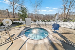 A hot tub with a metal railing, a sign, and a chair on a concrete deck with a view of trees and mountains. - 3x 2BR Condos: 1 mile to Christmas Lights (Leavenworth)