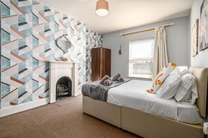 A bedroom with a bed, a fireplace, a wardrobe, and a window with curtains. - Modern 6-bed House in Bedford (Bedford)