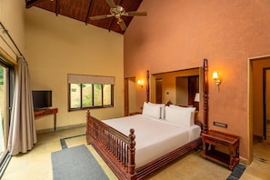 A spacious bedroom with a large bed, a ceiling fan, a television, and a window with curtains.