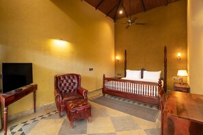 A hotel room with a bed, a television, a chair, a desk, and a ceiling fan.