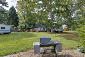 Un jardin avec un barbecue, des arbres et une maison.