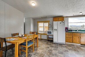 A compact kitchen with a dining area, wooden cabinets, a built-in microwave, and a window with a view.