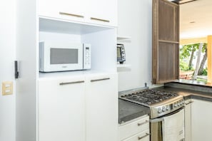 Eine Küche mit einer eingebauten Mikrowelle, einem Herd und einem kleinen Kühlschrank.