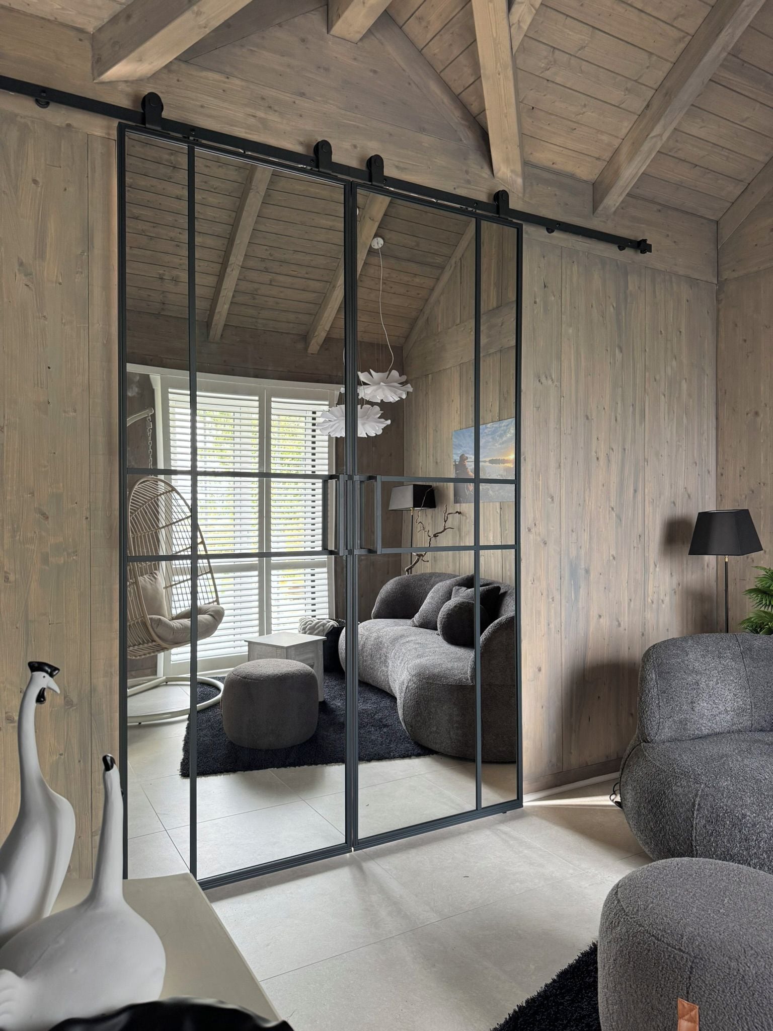 A room with a sliding glass door, a sofa, a chair, a lamp, and a decorative bird sculpture.