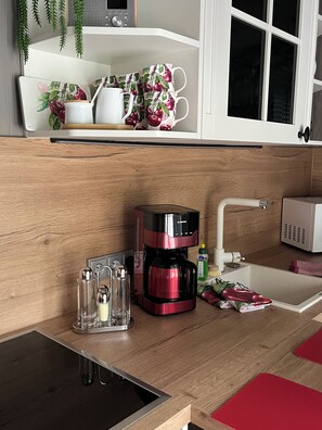 Eine moderne Küche mit Kaffeemaschine, Salz- und Pfefferstreuern, einer Mikrowelle und einem Spülbecken.
