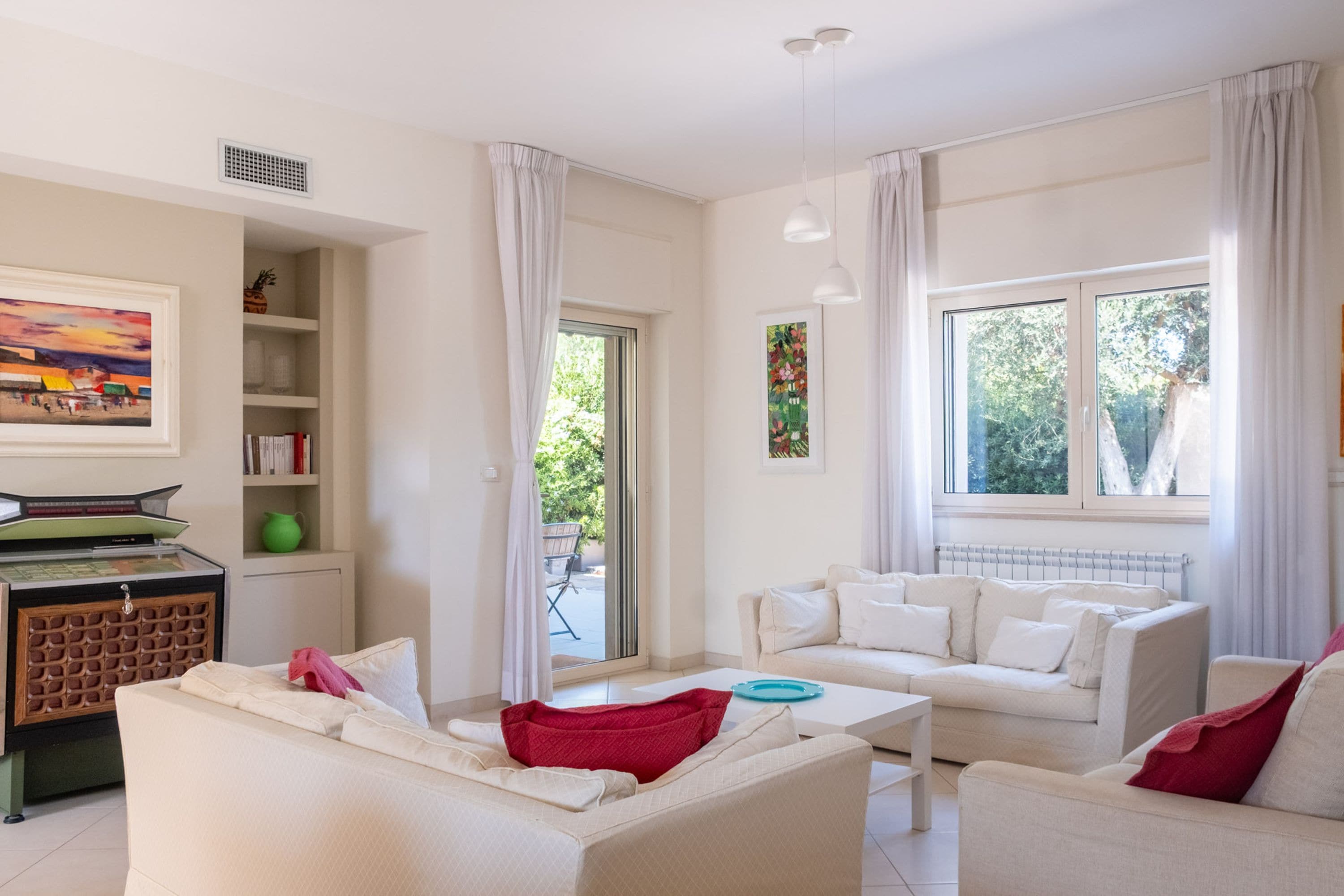A modern living room with a white sofa set, a coffee table, and a bookshelf with books and decorative items.