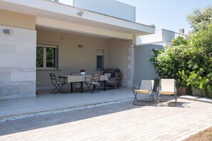 An outdoor patio with a dining table and chairs, a small grill, and a potted plant. - Villa Andrews by Wonderful Italy (Bari)