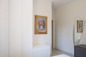 A bedroom with a white dresser, a mirror, and a painting on the wall. - Villa Andrews by Wonderful Italy (Bari)