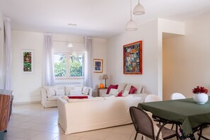 A modern living room with a white sofa, a dining table with chairs, and artwork on the walls. - Villa Andrews by Wonderful Italy (Bari)