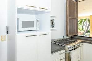 Una cocina compacta con microondas integrado, cocina a gas y refrigerador pequeño.