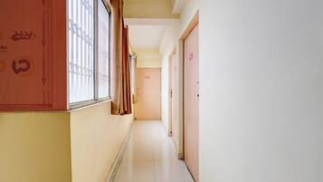 Un pasillo con una ventana a la izquierda, una puerta a la derecha y una pared con un letrero de precaución.
