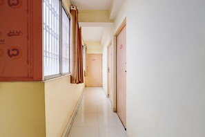 Un pasillo con una ventana a la izquierda, una puerta a la derecha y una pared con un letrero de precaución.