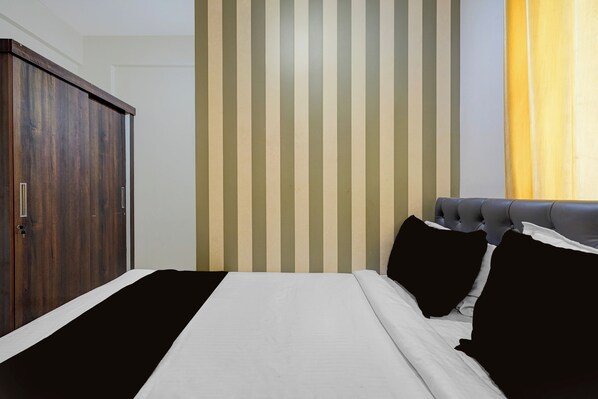 A bedroom with a bed, a wardrobe, and a striped wall. - Hotel O Ambedkar Nagar Bus Terminal (Bengaluru)