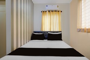 A hotel room with a bed, a window with curtains, a wall-mounted air conditioner, and a striped wall. - Hotel O Ambedkar Nagar Bus Terminal (Bengaluru)