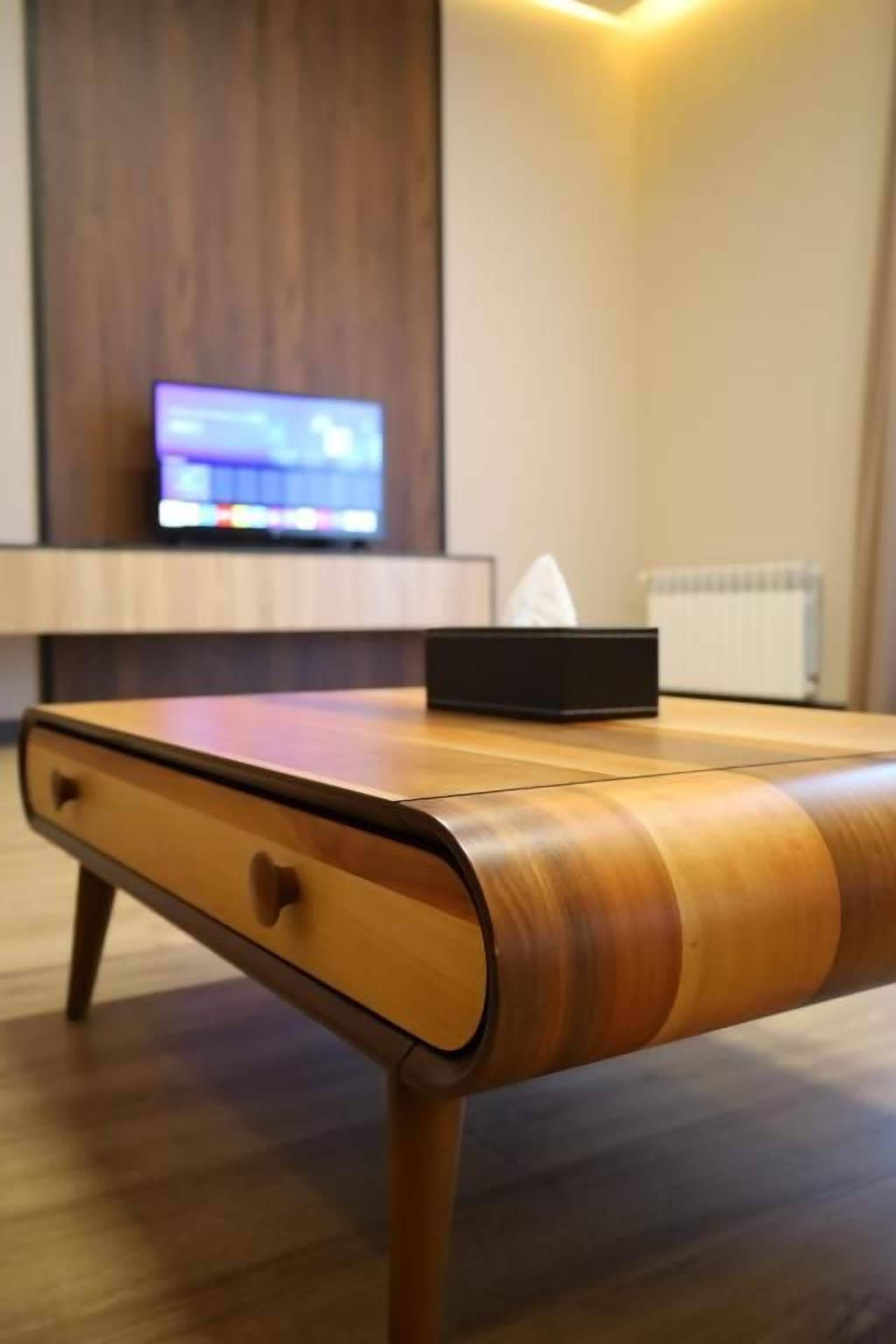 Una mesa de madera con un cajón, una caja negra y un control remoto encima.