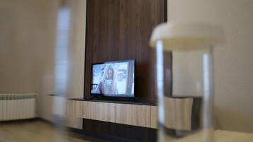 A television on a wooden stand in a room with a white radiator and a lamp.