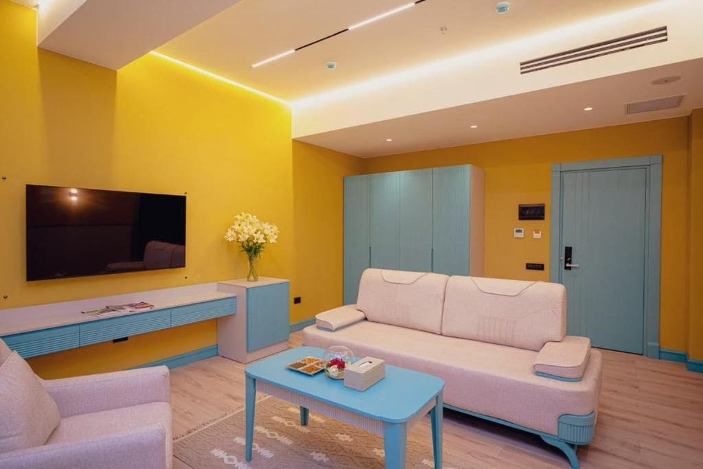Una sala de estar moderna con un televisor de pantalla plana, un sofá, una mesa de centro y una mesita auxiliar.