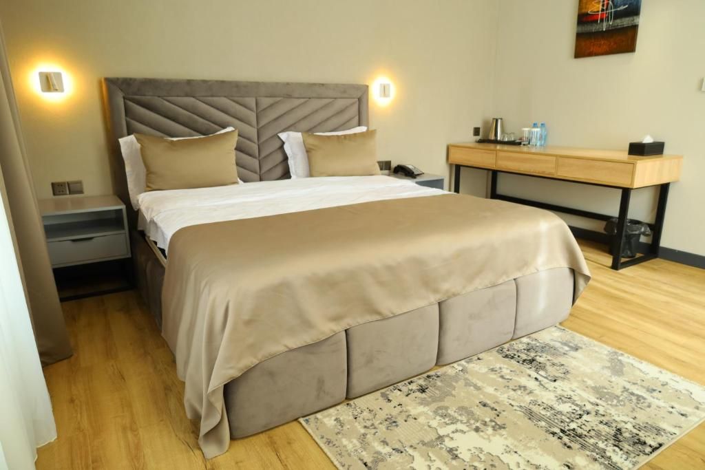 A bedroom with a bed, bedside tables, a desk, and a rug.