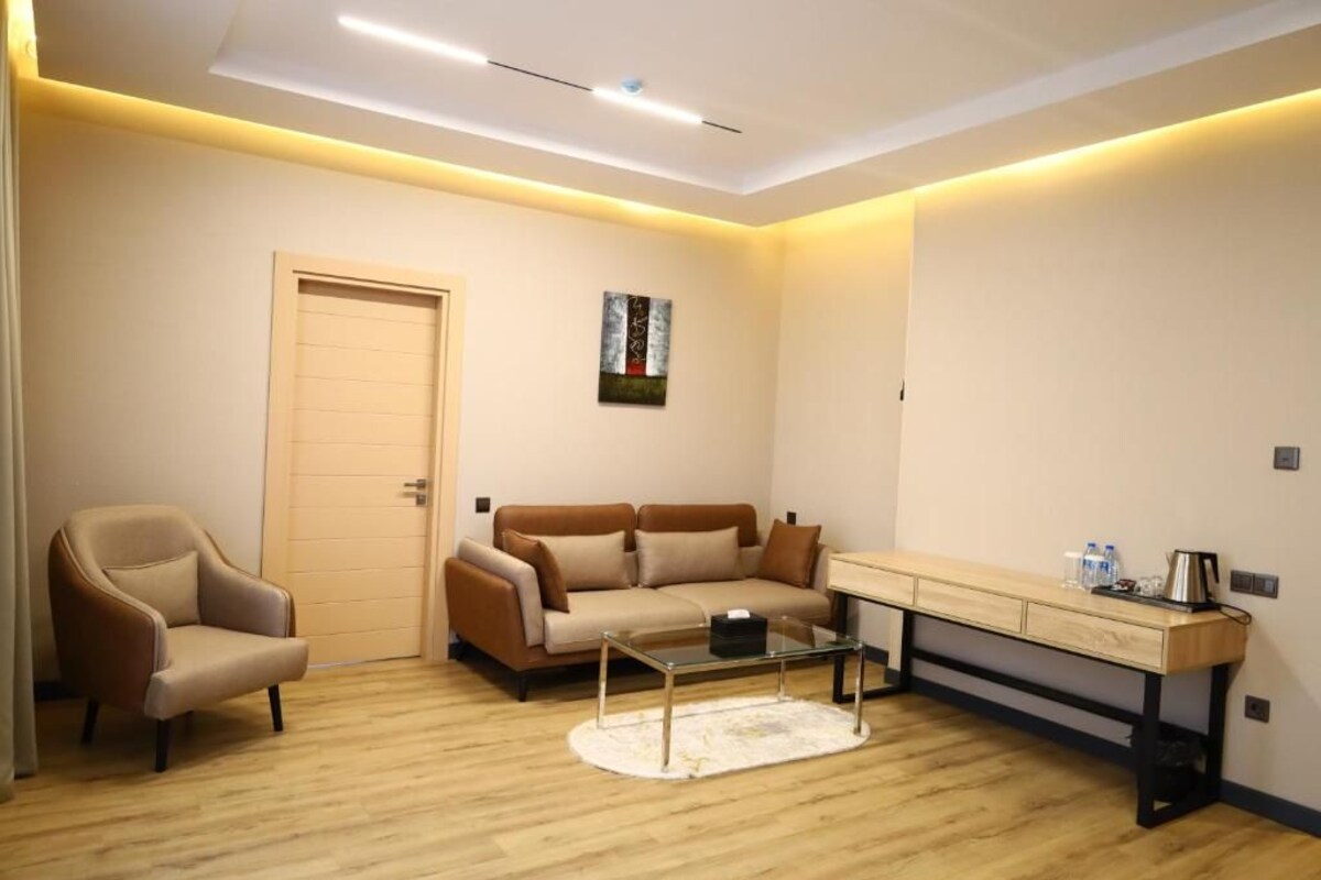 A modern living room with a sofa, armchair, coffee table, and a desk with drawers.
