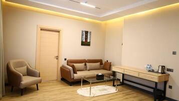 A modern living room with a sofa, armchair, coffee table, and a desk with drawers.