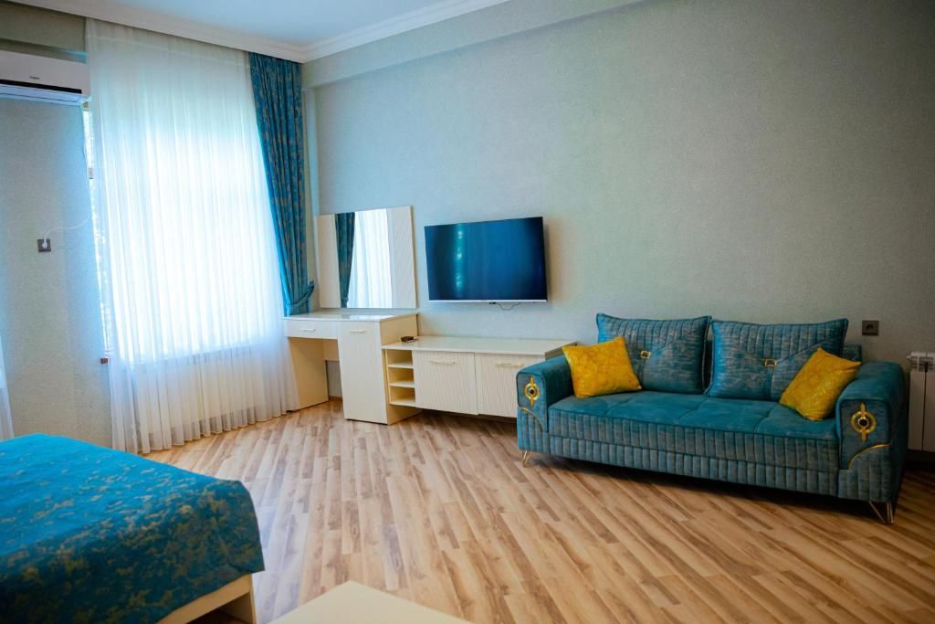 A hotel room with a bed, a sofa, a TV, and a desk.