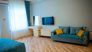 A hotel room with a bed, a sofa, a TV, and a desk.