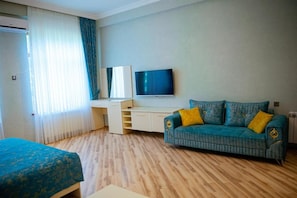 Una habitación de hotel con cama, sofá, televisor y escritorio.