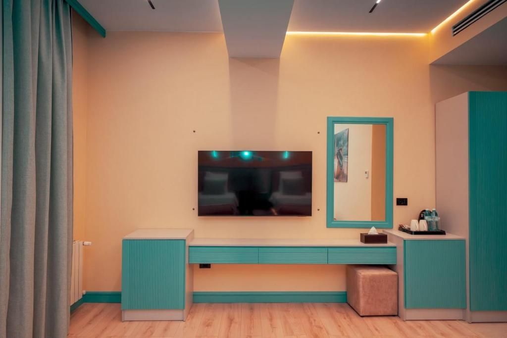 Une salle de bain moderne avec un grand miroir, un meuble-lavabo et un téléviseur fixé au mur.