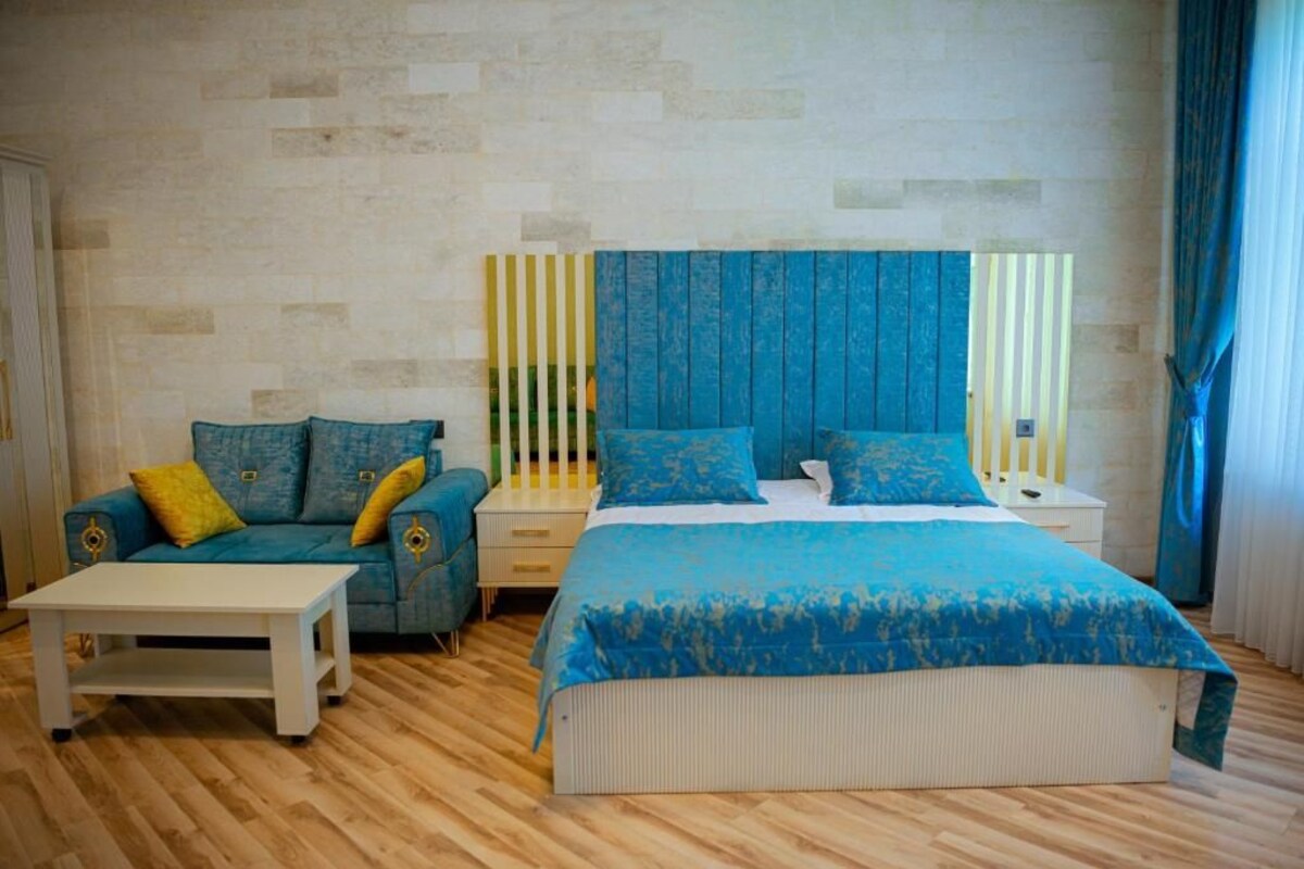 A bedroom with a large bed, a sofa, a nightstand, and a small table.